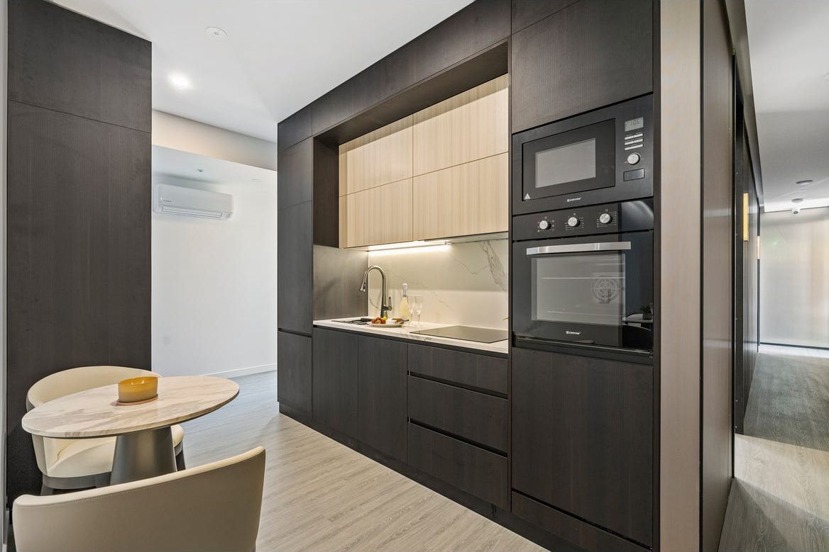 Kitchenette with dark joinery and a marble splashback in a Harmony co-living suite