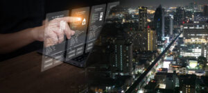 Businessman using futuristic digital interface for property management strategy and real estate data analytics with city nightscape. PropTech, smart investment, digital transformation.