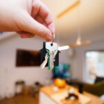 Hand holding house keys inside a rental property.