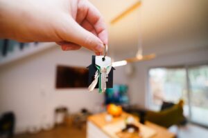 Hand holding house keys inside a rental property.