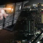 Businessman using futuristic digital interface for property management strategy and real estate data analytics with city nightscape. PropTech, smart investment, digital transformation.