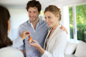 A couple receiving house keys, representing a stable rental property investment.